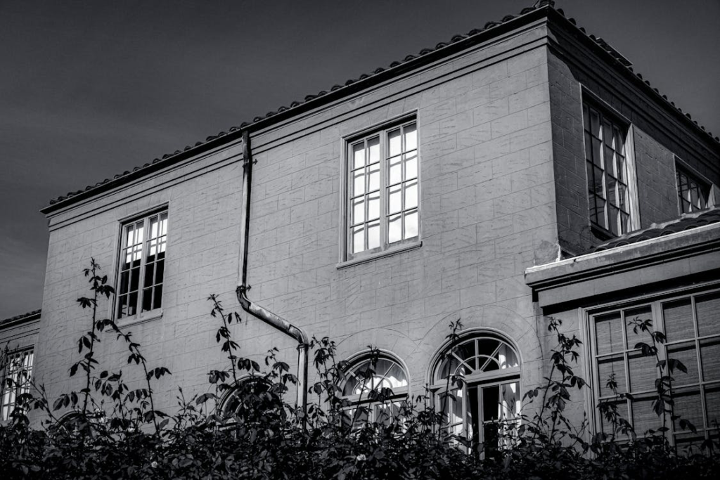Black and white photo of a clean house exterior with a long gutter pipe running along the wall.