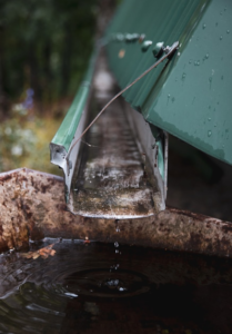 Close-up of a clogged gutter downspout overflowing with debris.