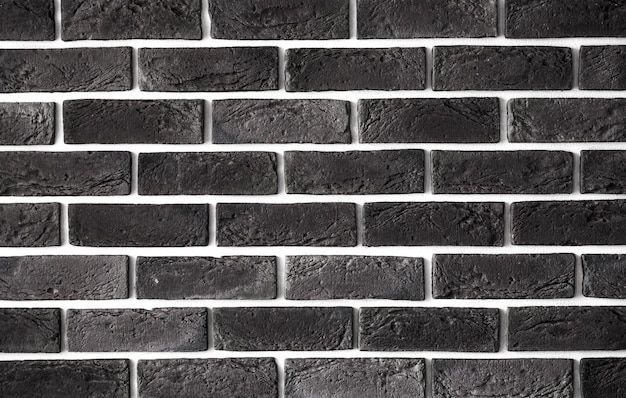 Close-up of a dark brown brick wall with a textured surface.