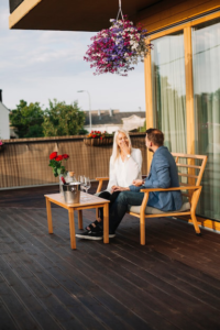 Smiling young couple sitting on a wooden deck, enjoying a date.