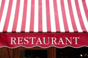Faded red and white striped canvas awning over a restaurant storefront.