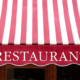 Faded red and white striped canvas awning over a restaurant storefront.