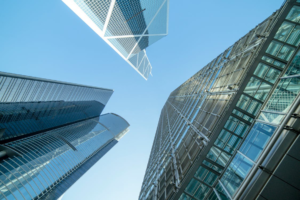 Low-angle view of modern skyscrapers reaching towards a clear blue sky with white clouds.