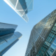 Low-angle view of modern skyscrapers reaching towards a clear blue sky with white clouds.