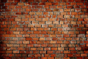 Close-up of a weathered red brick wall with stains and signs of wear.