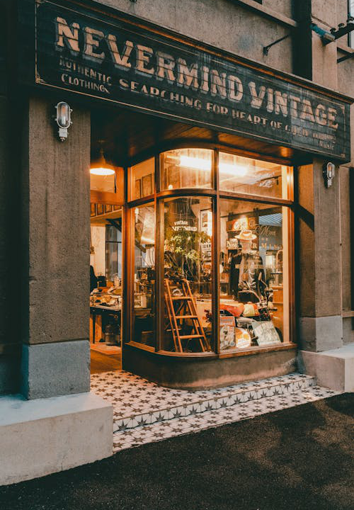 Clean sidewalk in front of a retail store with an illuminated window display and entrance.
