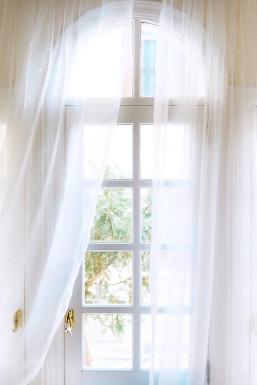 White curtains gently frame a clean window, allowing natural light to brighten the room.