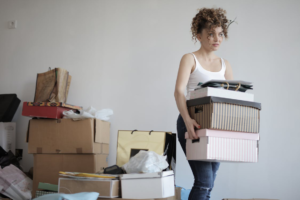 Woman carrying a stack of cardboard boxes for relocation.