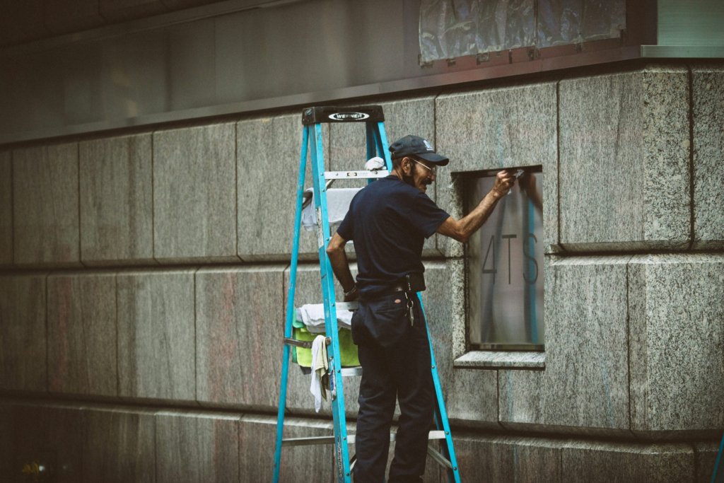 person on a ladder cleaning 